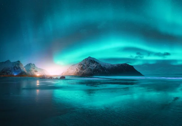 Aurora Borealis visible over a calm sea and mountains